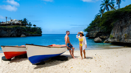 A couple of men and women at the beach of Playa Lagun with a fishing boat at the Island of Curacao,...