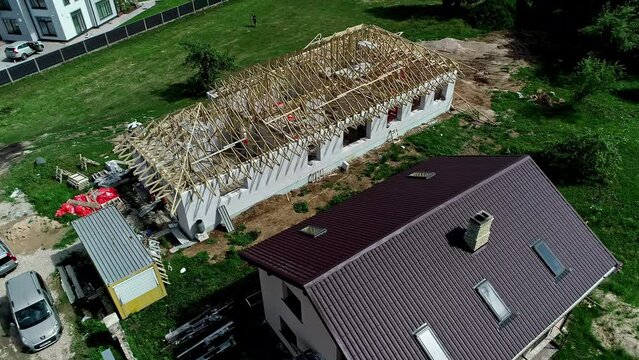 360-degree view of a under construction house with wooden frame for the roof near other houses 