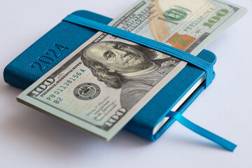 US 100 dollar banknote and busuness diary on whte background