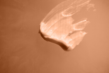 A smear of cream on a light background. Beauty concept. Color peach fuzz.