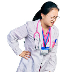 Fototapeta premium Young chinese woman wearing doctor uniform and stethoscope suffering of backache, touching back with hand, muscular pain