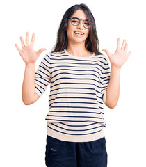 Brunette teenager girl wearing casual clothes and glasses showing and pointing up with fingers number ten while smiling confident and happy.