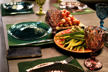 Elegant dining setup with vintage blue glassware; a plate of fresh vegetables adds a touch of...