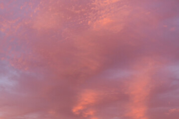 Warm hues adorn the sky as evening clouds reflect the setting sun's glow. Copy space background.