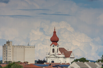 landscape with a nice church and houses during dense clouds at the blue sky detail