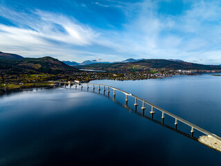 aerial view of Tresfjord Bridge with mountains on background with reflections on water in norway