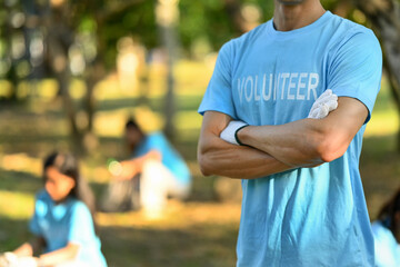 Man in volunteer uniform standing with arms crossed while standing outdoor. Charity and community service concept