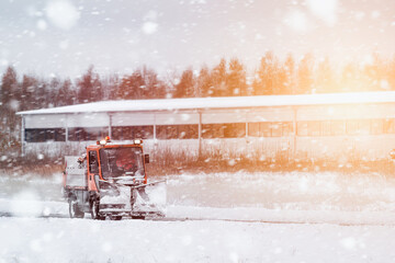 Road maintenance in winter. a tractor equipped with a spreader sprays a salt and sand mixture on...