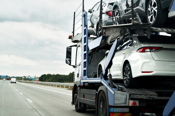 A flatbed tow truck transporting a damaged car on the highway, after a collision with another...