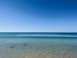 Calm blue ocean horizon, clear blue sky, sea surface background