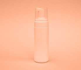 Empty white packaging tube for beauty spa, medical skin care and cosmetic lotion cream packaging, face wash foam, product design layout on pink background Peach fuzz is color of year 2024 tinted image