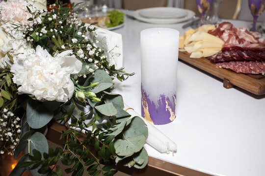 A decorative beautiful candle on a served wedding table for newlyweds, in a banquet hall. Image on the theme of weddings, decor and celebration.