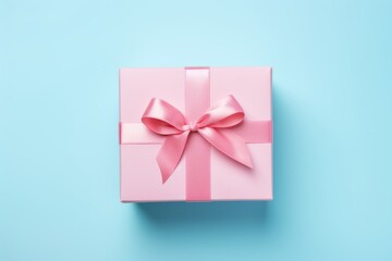 A picture of a pink gift box with a pink ribbon and bow on a blue background. Flat lay, top view