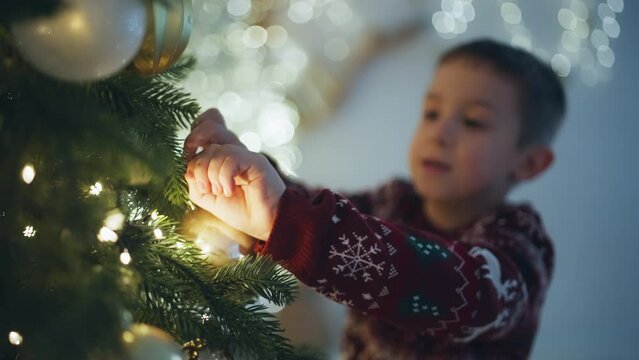 Festive Joy: Smiling Boy Decking the Halls, Decorating the Christmas Tree in Anticipation of Santa's Arrival. High quality 4k footage