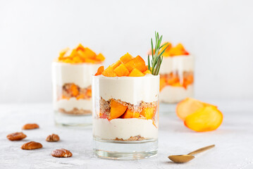 Parfait with persimmon, rosemary, pecan, whipped coconut cream and biscuit. Healthy food, vegan, sugar, gluten and lactose free. - obrazy, fototapety, plakaty