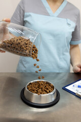 Dry food is poured into a bowl for the animal from a glass jar.