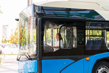 Woman bus driver driving city shuttle bus. Female occupation and public transportation.