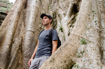 Caucasian Tourist in Front of The Big Trunk And Roots Of a Giant Tree in Ta Prohm, Angkor Wat, Siem Reap, Cambodia
