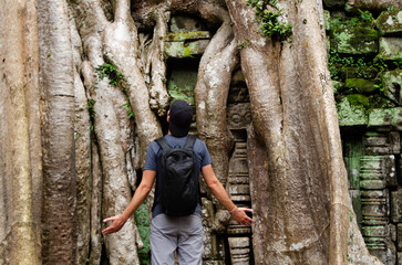Unrecognizable Caucasian Tourist in Front of The Big Trunk And Roots Of a Giant Tree in Ta Prohm,...