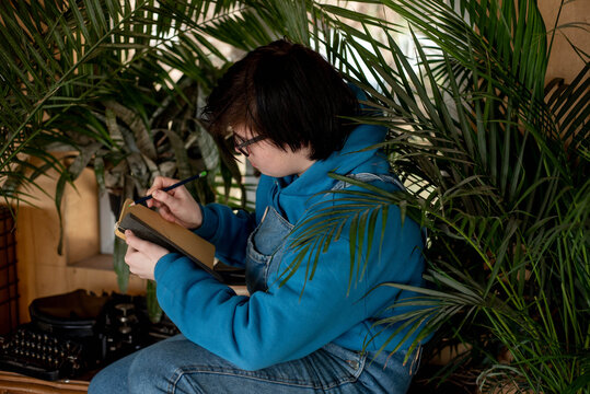 Portrait of a happy smiling neutral gender teenager surrounded with indoor plants