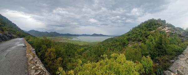 Fototapeta na wymiar Panoramic view of the shores of Lake Skadar, framed by mountains and covered with mud, on a cloudy day