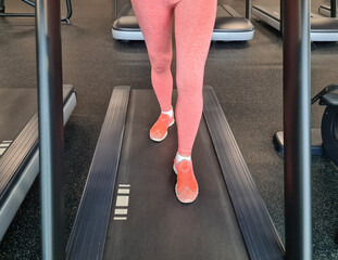 Woman using incline threadmill in modern gym. Incline treadmills are used to simulate uphill walking