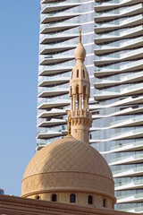 The minaret of the city mosque against the backdrop of a modern skyscraper. Preservation of...