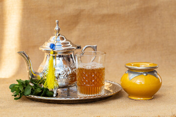 close up of moroccan traditional tea pot and glass on a silver plate
