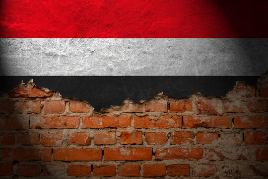 A wall with a painting of the yemen flag at night.