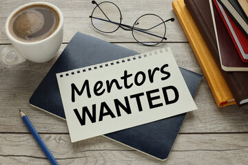 Mentor Wanted glasses lie near a cup of coffee. text on a notebook