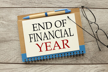 End of Financial Year. glasses on a notepad. top view of text - obrazy, fototapety, plakaty