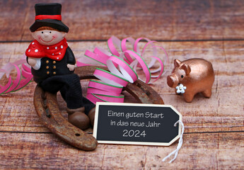 Einen guten Start in das neue Jahr 2024: Schornsteinfeger, Glücksschwein und Hufeisen mit Glückwünschen für das neue Jahr.