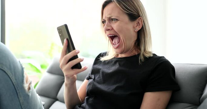 Woman learning bad news and screaming into mobile phone at home 4k movie slow motion. How to deliver bad news concept