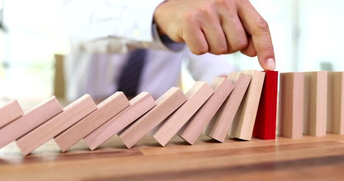 Insurance agent hand stopping falling wooden blocks closeup 4k movie. Insurance and risk prevention guarantees concept