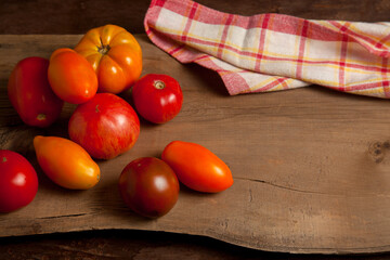 Assort of different shape and color tomatoes on wooden background..