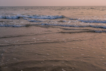 Fototapeta premium foam of sea or ocean waves against the backdrop of the setting sun
