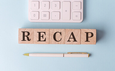 RECAP on wooden cubes with pen and calculator, financial concept