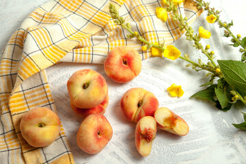 Halves and several whole saturn peaches or flat peach on white wooden background..