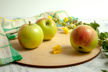 Three green apples on white wooden background..