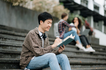 Obraz premium Female students note from the books at the Asian girl library sitting at the campus park using laptop computer and tablet to search an online informations.