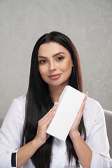 Beautiful female medical specialist holding small box with copy space indoors. Portrait of...