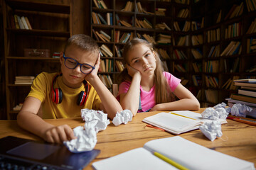 Exhausted children cannot do their homework sitting at table