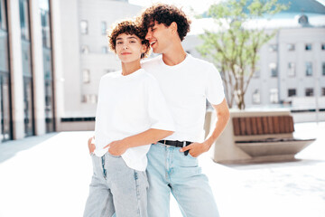 Young smiling beautiful woman and her handsome boyfriend in casual summer white t-shirt and jeans clothes. Happy cheerful family. Female having fun. Couple posing in street at sunny day