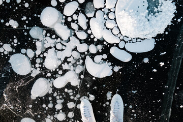 Skates close up on the frozen bubbles inside a frozen lake ice. Winter landscape, sunny day,...
