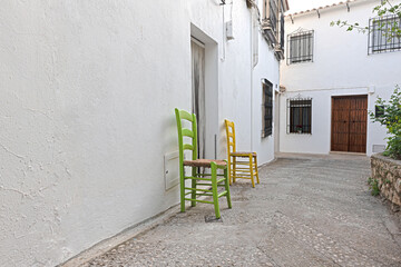 Fototapeta na wymiar Typical white andalusian village white street with chairs outside the house