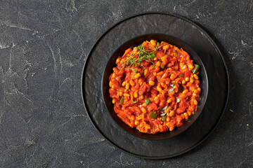 chakalaka, spicy tomato bean relish in black bowl