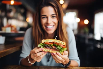 Fotobehang woman eating sandwich with crispy bacon in a caf꧃� © primopiano