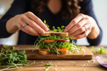 Foto auf Acrylglas woman taking a bit of delicious sandwich with microgreen © primopiano