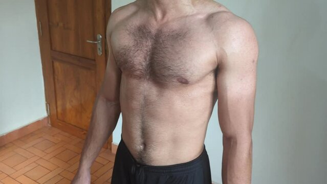 cropped pan video of a young athletic man flexing his abs and muscles after an intense workout training in the gym