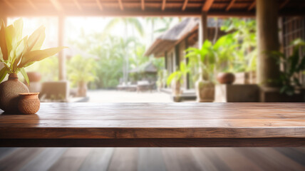 An empty wooden table foregrounds a blurred Balinese-style interior, inviting a serene and tropical atmosphere perfect for a calm setting. - obrazy, fototapety, plakaty